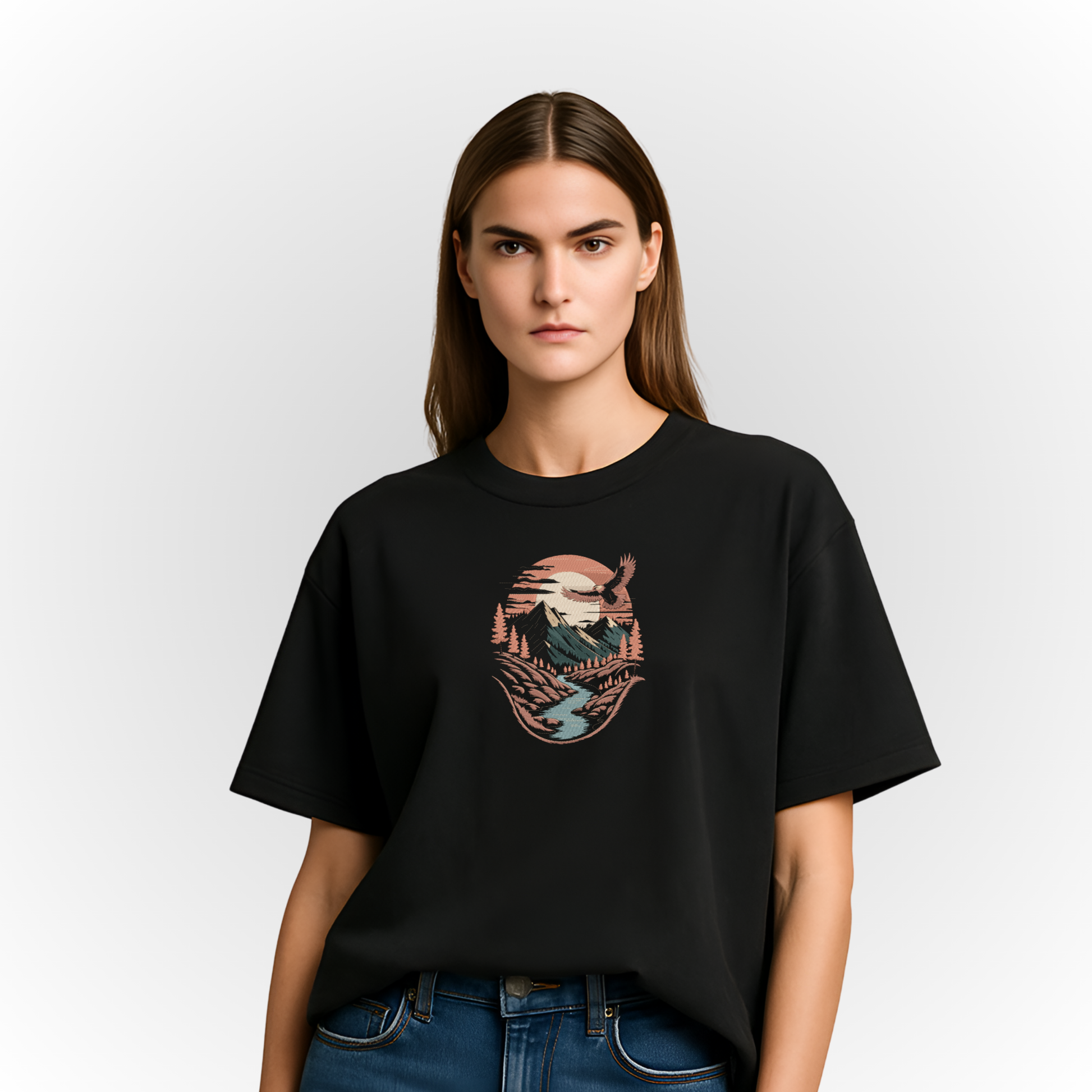 Person wearing a black t-shirt with a Mountain river landscape embroidery on a white background